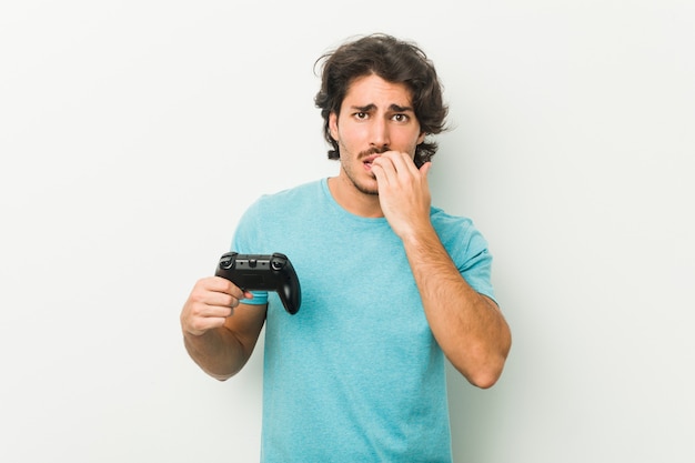 Joven sosteniendo un controlador de juego mordiendo las uñas, nervioso y muy ansioso.