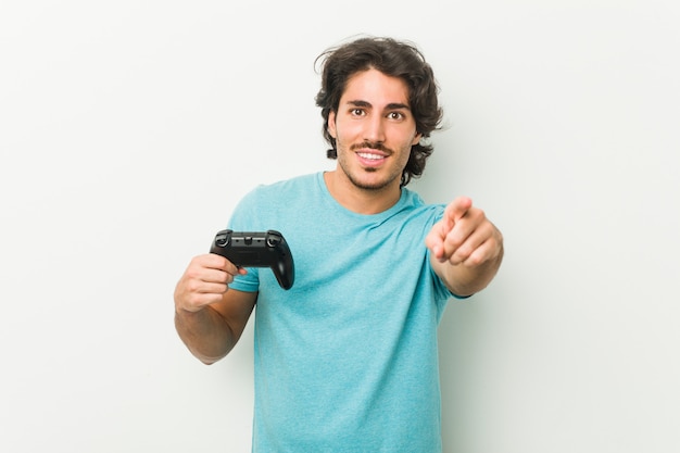 Joven sosteniendo un controlador de juego sonrisas alegres apuntando al frente.