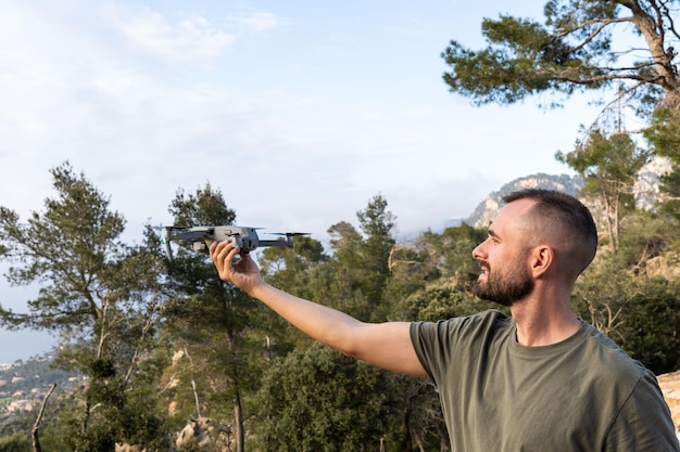 Joven sosteniendo un dron antes del vuelo en la naturalezaGuy se prepara para pilotar al aire libre
