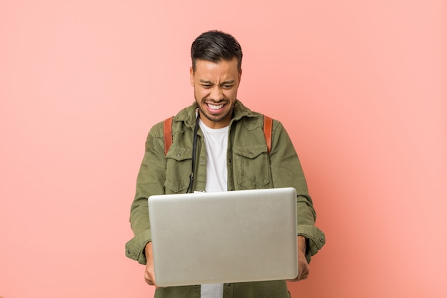 Joven sosteniendo una laptop.