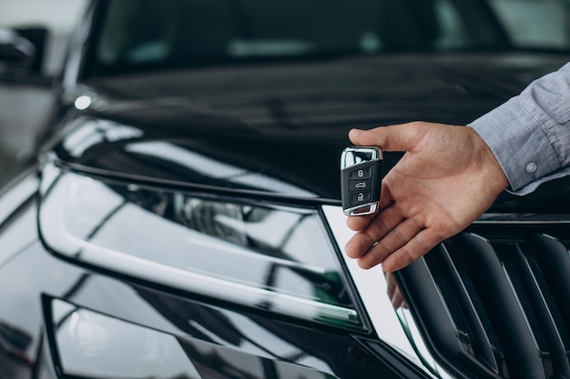 Joven sosteniendo las llaves del coche por su coche nuevo