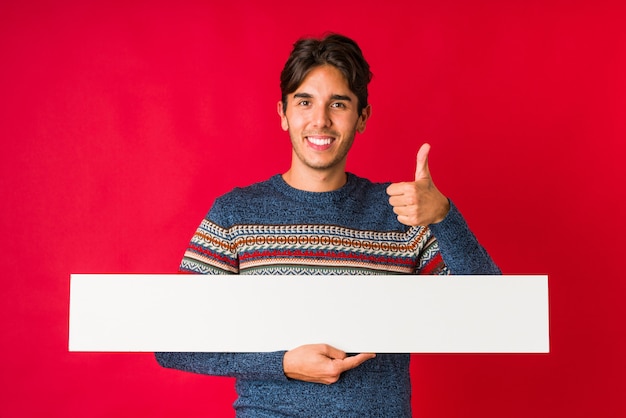 Joven sosteniendo una pancarta sonriendo y levantando el pulgar