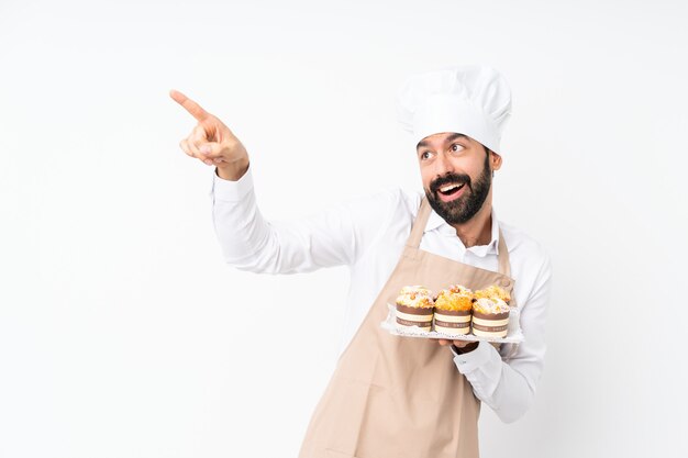 Joven sosteniendo pastel muffin apuntando lejos