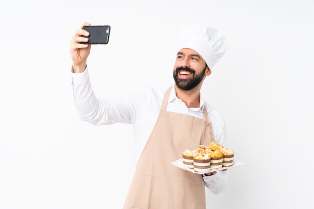 Joven sosteniendo pastel de muffin sobre blanco aislado haciendo un selfie