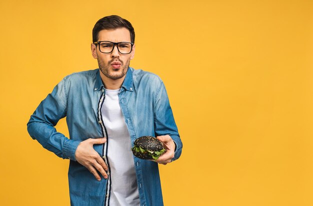 Foto joven sosteniendo un pedazo de sándwich el estudiante come comida rápida la hamburguesa no es un alimento útil