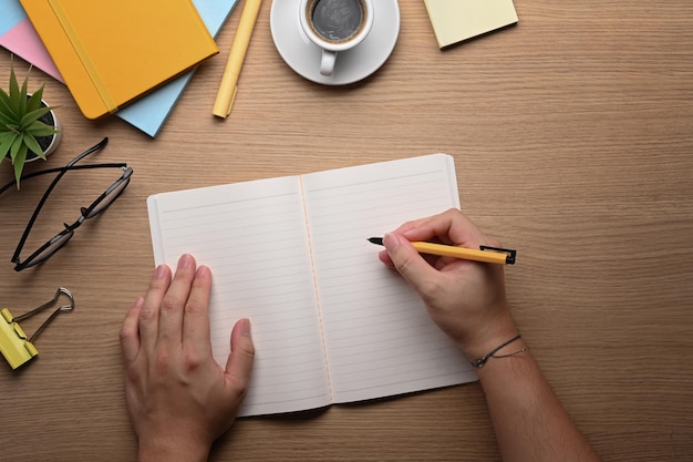 Joven sosteniendo la pluma y escribiendo en el cuaderno.