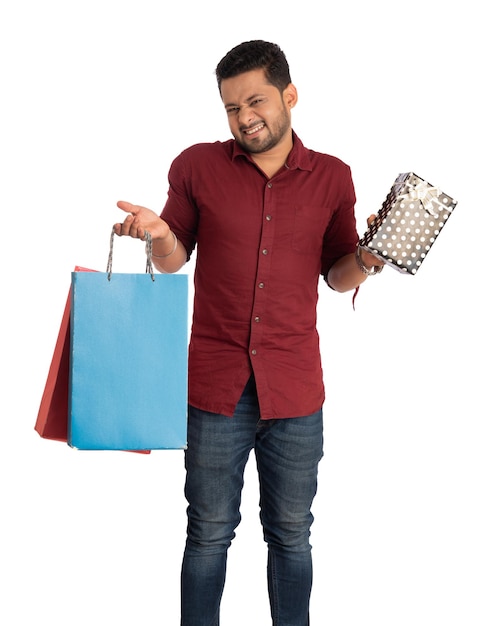 Joven sosteniendo y posando con bolsas de compras y cajas de regalo en un fondo blanco