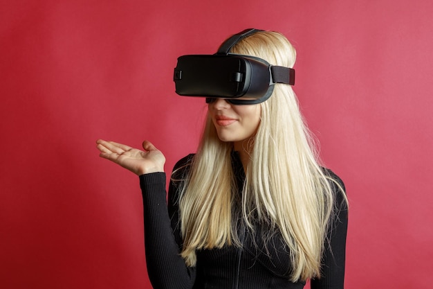 Joven sosteniendo su mano abierta y usando gafas VR sobre fondo rojo.