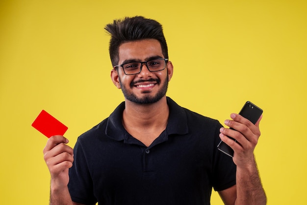 Joven sosteniendo la tarjeta de visita en el estudio de fondo amarillo.