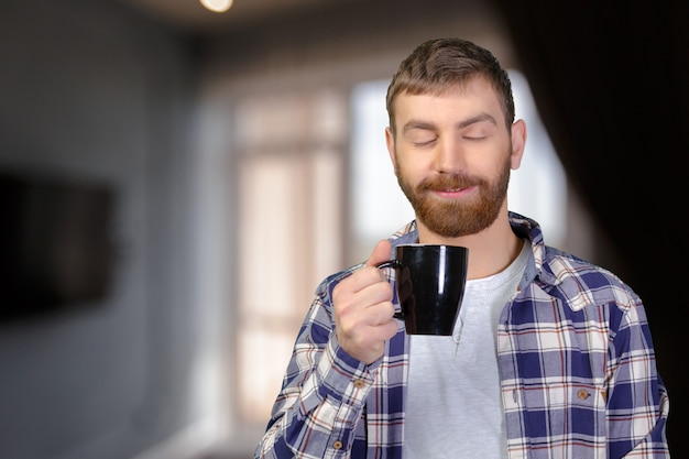 Joven sosteniendo una taza caliente de té / café