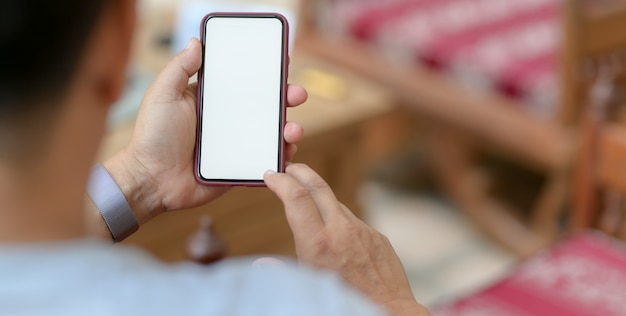 joven sosteniendo el teléfono inteligente en la cómoda sala de oficina