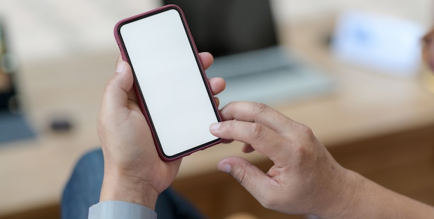 joven sosteniendo el teléfono inteligente en la cómoda sala de oficina