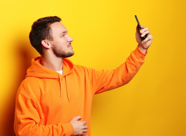 Joven sosteniendo teléfono móvil y haciendo fotos