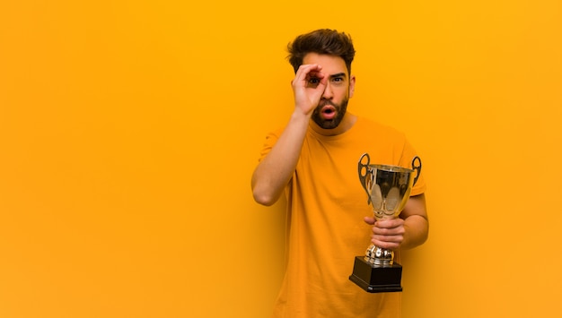 Joven sosteniendo un trofeo haciendo el gesto de un catalejo