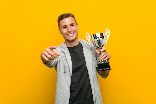 Joven sosteniendo un trofeo sonrisas alegres apuntando al frente