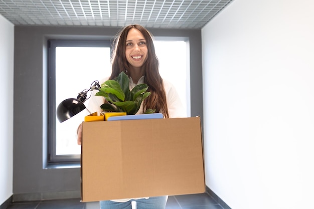 Una joven sostiene una caja de cartón en sus manos mientras solicita un nuevo trabajo