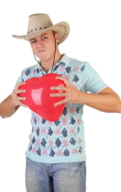 El joven sostiene un globo rojo en forma de corazón aislado sobre un fondo blanco.