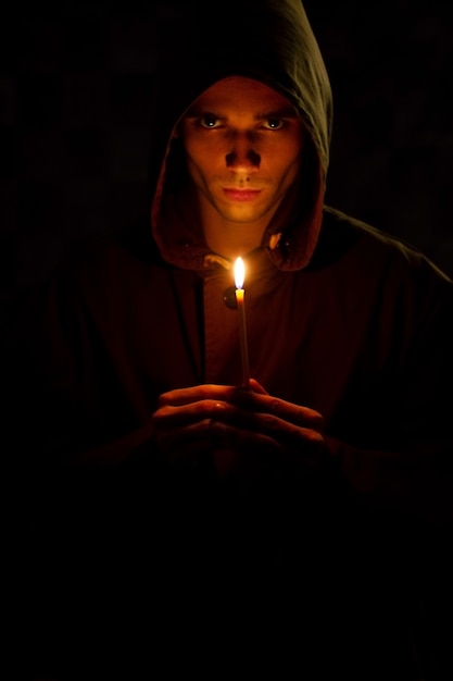 El joven sostiene una vieja vela que ilumina la oscuridad.