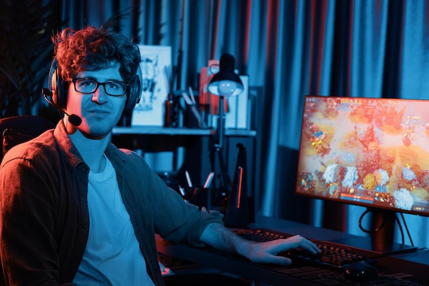 Joven streamer de juegos mirando a la cámara contra el gusher de la pantalla de moba