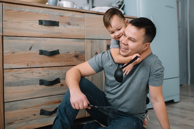 Foto joven y su hijo jugando en la cocina