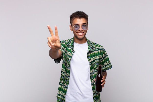 Joven sudamericano sonriendo y mirando feliz, despreocupado y positivo, gesticulando victoria o paz con una mano