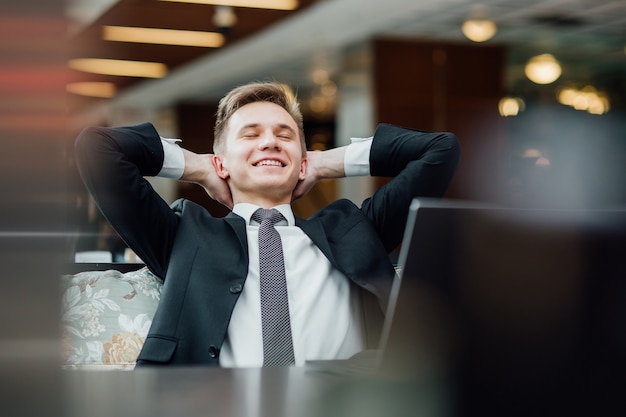 Joven sueña con vacaciones, se relaja después de un duro día de trabajo después de una computadora portátil en la cafetería