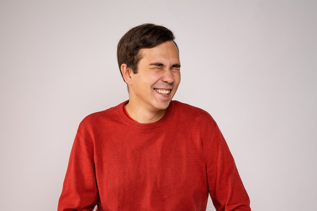 Un joven con un suéter rojo se ríe. Retrato