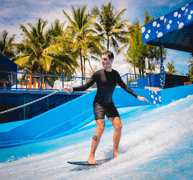 Un joven surfeando en un simulador de olas en un parque de atracciones acuáticas