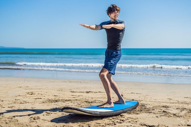 Joven surfista entrenando antes de ir a la alineación en una playa de arena. Aprendiendo a surfear. Concepto de vacaciones. Vacaciones de verano. turismo, deporte