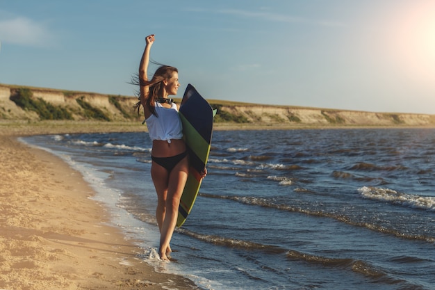 Joven surfista posando con su tabla de surf en la playa