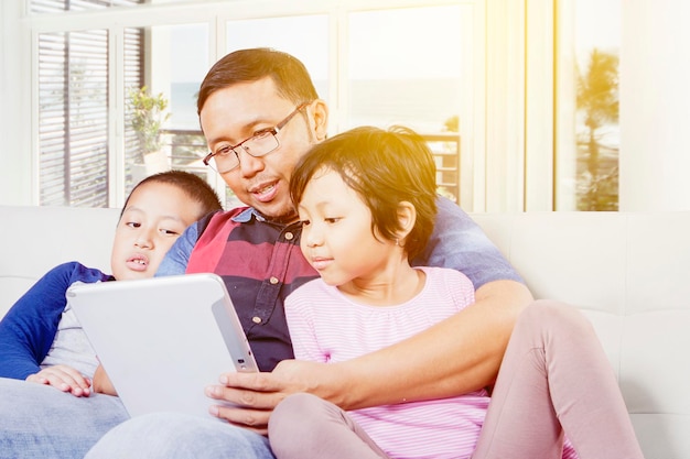 Joven y sus hijos usando tableta en casa