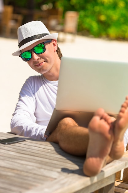 Joven con tablet PC durante vacaciones en la playa tropical