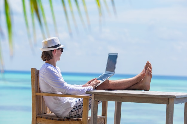 Joven con tablet PC durante vacaciones en la playa tropical