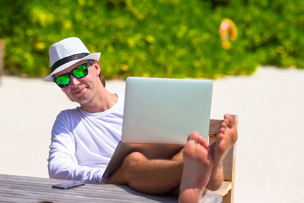 Joven con tablet PC durante vacaciones en la playa tropical