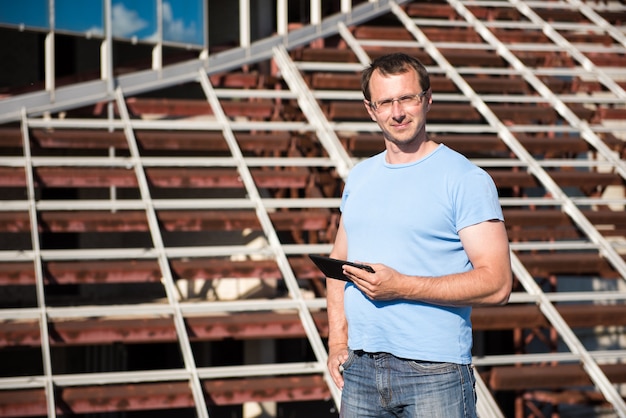 Joven con tableta se encuentra en las estructuras de construcción