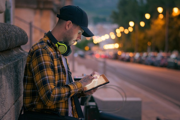 Joven con tableta iluminada en la calle por la noche