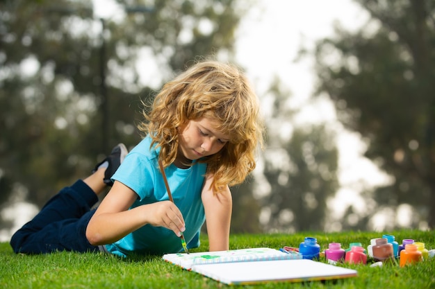 Joven talentoso artista pintor escolar niños dibujando en el parque de verano pintura arte pequeño pintor d