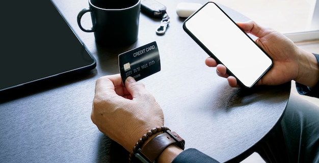 Joven con tarjeta de crédito comprando en una computadora portátil mientras está sentado en casa. Pago en línea, compras en línea.