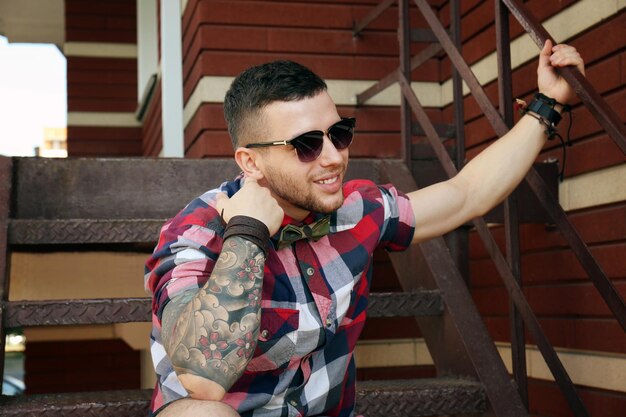 Foto joven tatuado posando en las escaleras al aire libre