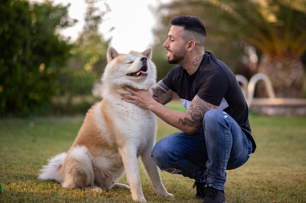 Joven con tatuajes feliz sonriendo con su perro