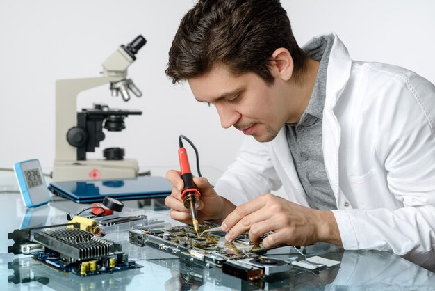 Joven técnico energético o ingeniero masculino repara equipo electrónico