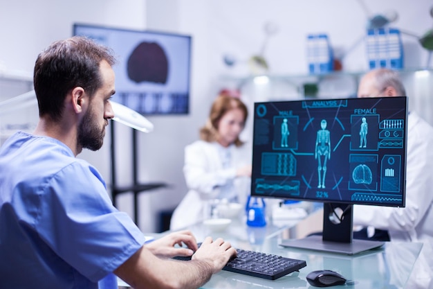 Joven técnico escribiendo datos para el sistema de neurología del cuerpo humano en el laboratorio de ciencias. Especialista en trabajo.