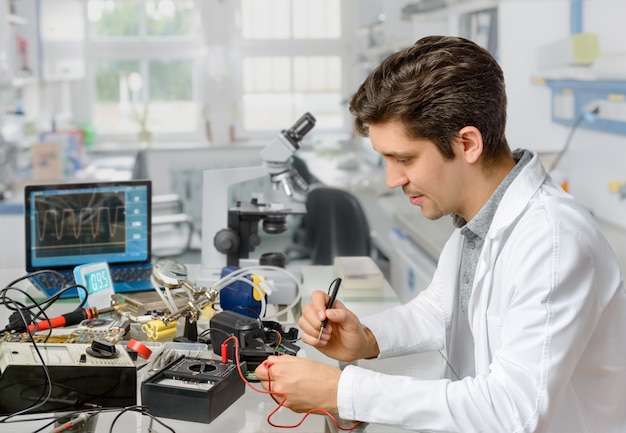 Joven técnico masculino o ingeniero repara equipo electrónico