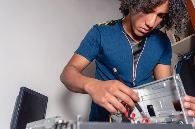 Joven técnico moreno trabajando en mantenimiento de computadoras