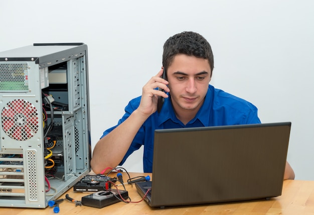 Foto joven técnico trabajando en computadora rota y llamar al cliente