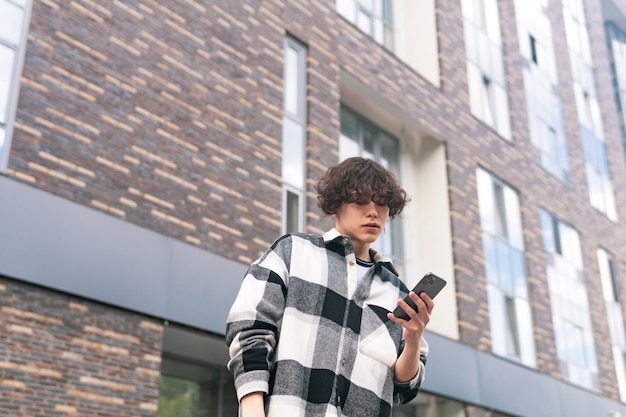 Joven con un teléfono en el fondo de los edificios de la ciudad