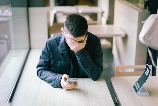 Un joven con un teléfono en la mano está sentado en un restaurante.