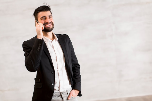 Joven con teléfono móvil junto a la pared