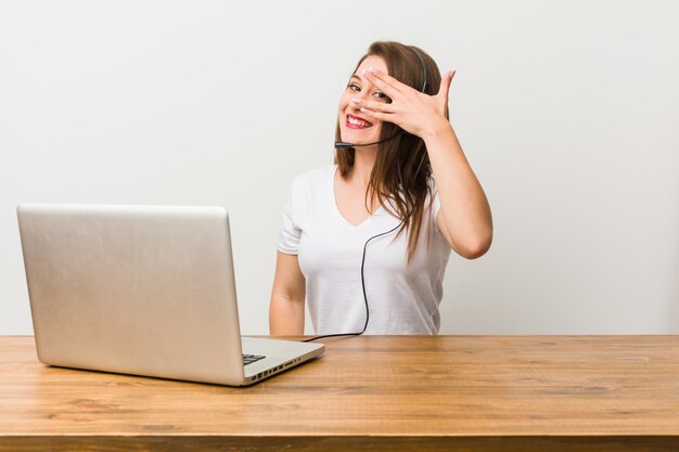 La joven teleoperadora parpadea entre los dedos, avergonzada cubriéndose la cara.