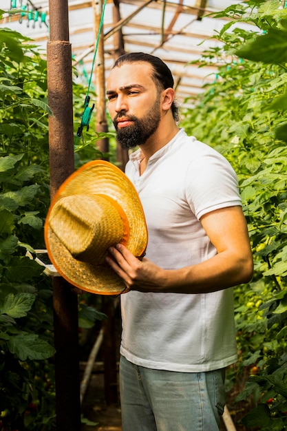 Foto joven, tenencia, sombrero, y, posición, en, el, invernadero